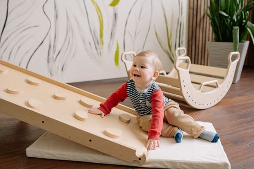 Joyful Child Playing on Wooden Slide image in article Montessori Magic at Home: Tips for Every Age